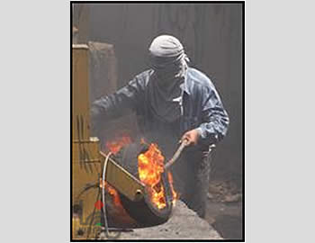 Un manifestante palestino pone fuego a un neumático durante la manifestación en Bil’ in 