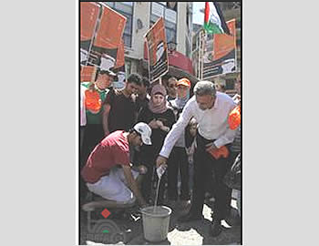 Les organisateurs de la campagne versent du lait israélien dans un seau (Wafa, 15 juillet 2012)