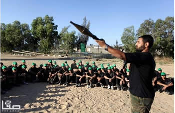 Children wearing green Hamas hats are shown how to fire an RPG at a Hamas summer camp (Filastin Al-'Aan, June 16, 2013).