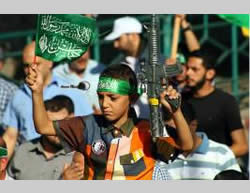 A child holds a plastic gun and a Hamas-affiliated flag.