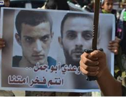 A sign with the pictures of the two terrorists. The Arabic reads, 