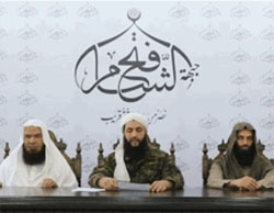 Al-Nusra Front leader Abu Mohammad al-Julani flanked by two officials from his organization, in an interview with Al-Jazeera TV in which he announces that the organization has been renamed the Fateh al-Sham Front (Al-Jazeera TV, July 28, 2016).  The insignia of the organization appears above, consisting of the name the Fateh al-Sham Front. In this interview with Al-Jazeera TV, Al-Julani appears unmasked for the first time.  