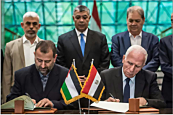 Azzam al-Ahmad (rechts), Leiter der Fatah-Delegation, und Salah al-Aruri (links), Chef der Hamas-Delegation, unterzeichnen das Versöhnungsabkommen in Kairo. Im Hintergrund sind Yahya al-Sinwar, Politbürochef der Hamas, der ägyptischen Geheimdienstminister und hochrangige Fatahaktivisten zu sehen (Wafa Nachrichtenagentur, 12. Oktober 2017)