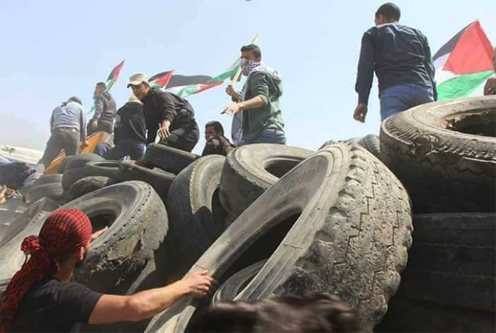 Palestinians collect tires in the eastern Gaza Strip for burning at the 