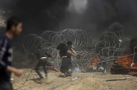 Palestinians attempt to vandalize the barbed wire fence (Facebook page of Shehab, April 13, 2018).