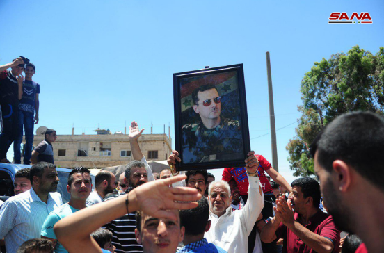 Residents of the town of Abta, north of Daraa, welcoming the arrival of the Syrian army and waving a picture of Syrian President Bashar Assad (SANA News Agency, June 29, 2018).