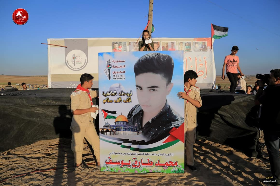 Sign, praising the terrorist who carried out the attack in the community of Adam, carried at the "return march" in eastern Jabalia (Facebook page of the "supreme national authority of the return march," July 28, 2018). 