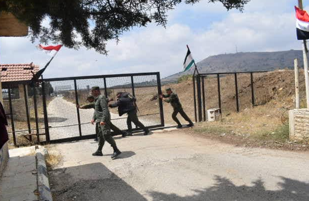 Syrian army soldiers opening the Quneitra crossing, with the Syrian flag waved above.