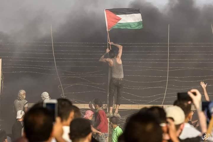 A Gazan hangs a Palestinian flag on the security fence east of Gaza City.