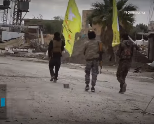 SDF fighters carrying flags walking in the streets of Hajin (YPG Press Office YouTube channel, December 15, 2018)