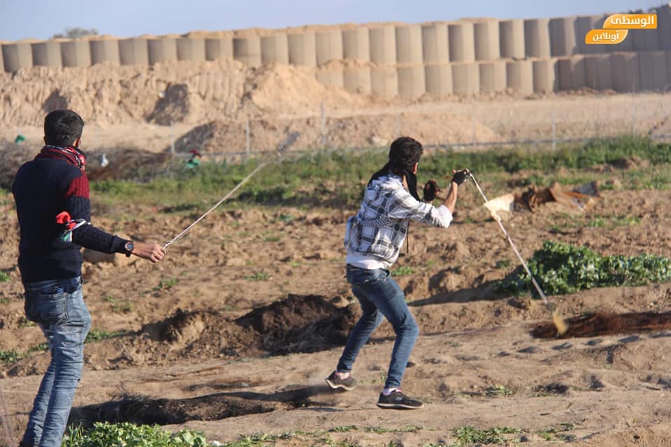  Young Palestinians sling throw near the security fence during the "return march" (Supreme National Authority Facebook page, February 23, 2019).