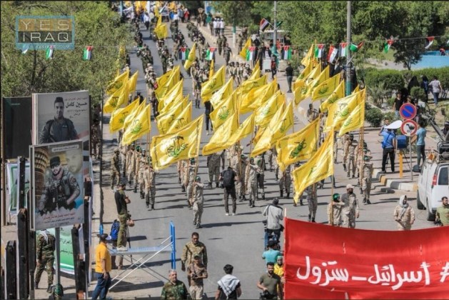 Jerusalem Day marchers wave flags of the al-Nujaba Movement of the Shi'ite militias, handled by the Iranian Qods Force. Marchers carry a sign reading "Israel_will disappear." 