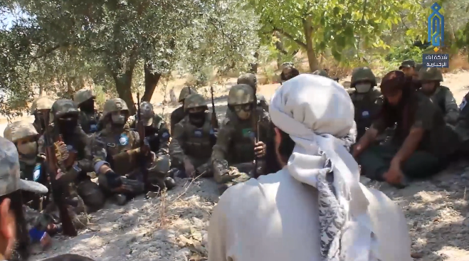 Operatives of the Headquarters for the Liberation of Al-Sham listening to a cleric a short while before setting out to halt a Syrian army attempt to advance towards the hill of Kabanah (Ibaa, August 26, 2019)