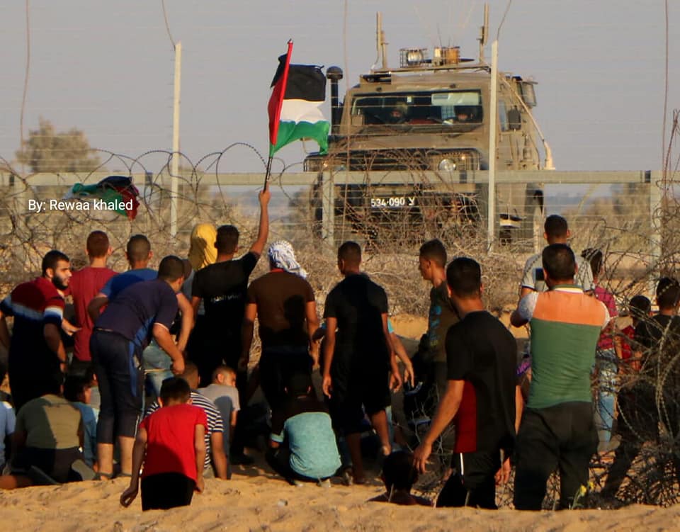 Des manifestants dans l'Est de Rafah agitent un drapeau palestinien près de la barrière de sécurité et d'un véhicule de Tsahal. 