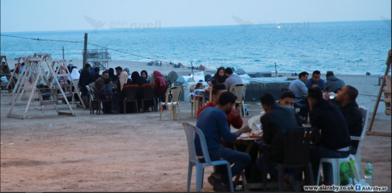 משפחות שוברות את צום רמצ'אן על חוף הים (אלערבי אלג'דיד, 5 במאי 2020). 