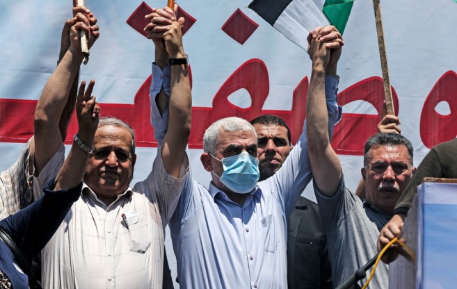 Yahya al-Sinwar (mask) holds the raised hand of senior Fatah figure Ahmed Hilles (right) in a show of unity (Shehab Twitter account, July 1, 2020).