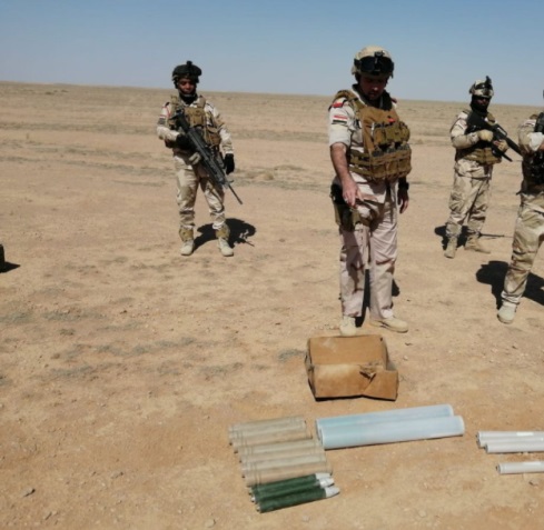 Un officier de l'armée irakienne et des soldats près de certaines des armes saisies.