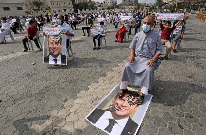 A demonstrator sits with his feet on a picture of French President Macron at a demonstration in Khan Yunis (Twitter account of photojournalist Ashraf Abu Amra, October 30 2020).