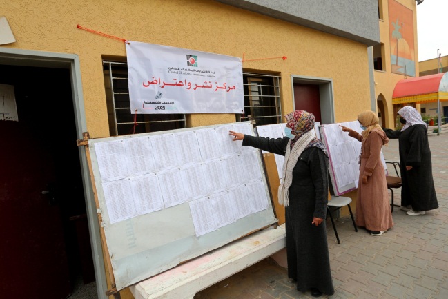 Palestinian women check for their names on the updated voter registration rolls at a school in Deir al-Balah (Twitter account of photojournalist Ashraf Abu Amra, March 1, 2021).