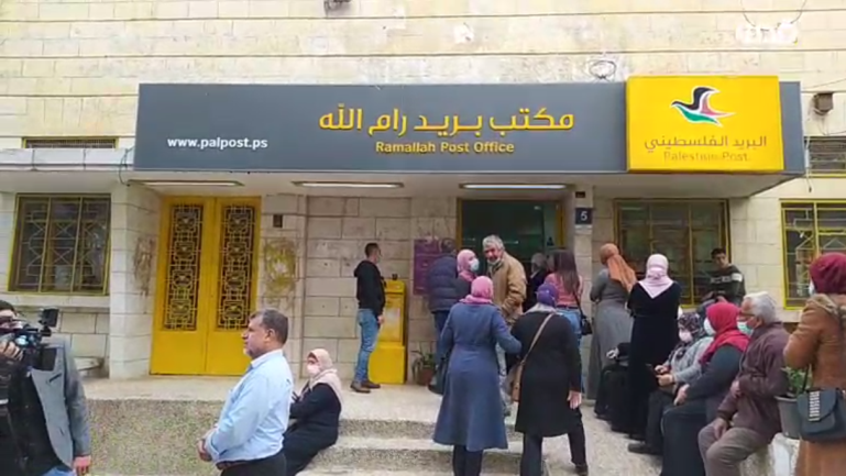 Released prisoners and the families of prisoners in Israeli jails wait in line at a post office bank branch in Ramallah (QudsN Facebook page, April 6, 2021).