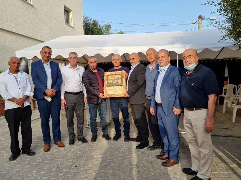 Jenin district governor Akram al-Rajoub at the home of terrorist operative Rushdi Abu Mukh. Abu Mukh holds the plaque and al-Rajoub is to his left (wearing a suit) (Akram al-Rajoub's Facebook page, April 7, 2021).