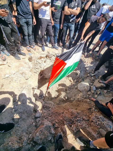 A rocket crater with Palestinian flag (Twitter account of Liam Baloum, May 15, 2021).