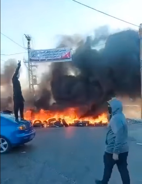 Masked Palestinians set tires on fire at the entrance to Anata, north of Jerusalem (QudsN Facebook page, May 18, 2021).