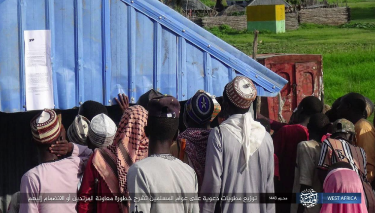 Residents looking at a poster put up by ISIS calling on them not to cooperate with the local authorities. 