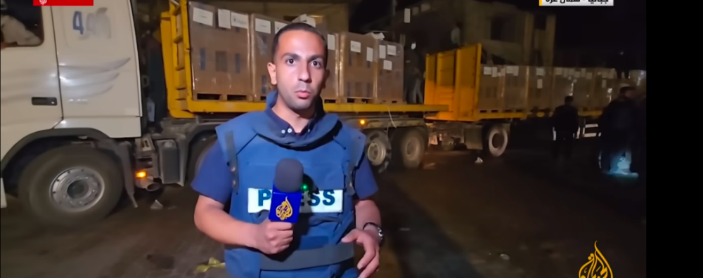 An al-Jazeera TV correspondent reports the arrival of the aid trucks at the Jebalya refugee camp (al-Jazeera YouTube channel, May 2, 2024)